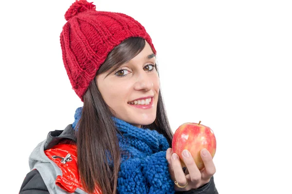 Joven morena sonriente con gorra de invierno, comiendo una manzana —  Fotos de Stock