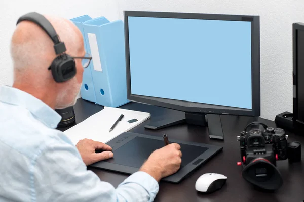 Homme mature travaillant avec tablette graphique dans son bureau — Photo