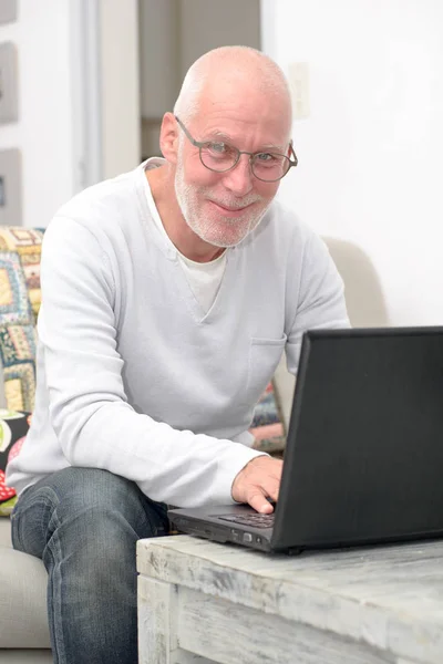 Homme âgé avec ordinateur portable assis dans le canapé — Photo