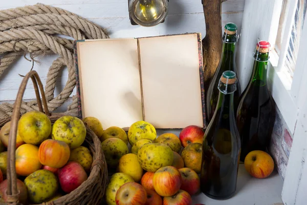 Cesta de maçãs, garrafas de cidra e caderno velho — Fotografia de Stock