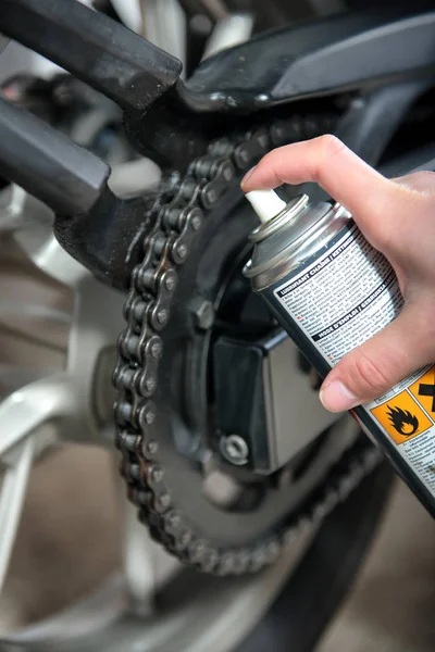 Lubricating motorcycle chain with chain spray grease — Stock Photo, Image