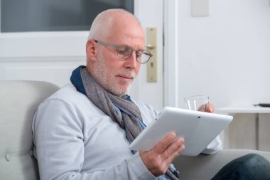 Olgun adam oturma odasında kanepede dijital tablet kullanma