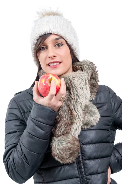 Joven morena sonriente con gorra de invierno, comiendo una manzana — Foto de Stock