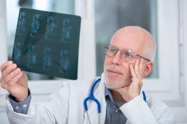 Doctor maduro mirando una radiografía en un consultorio —  Fotos de Stock