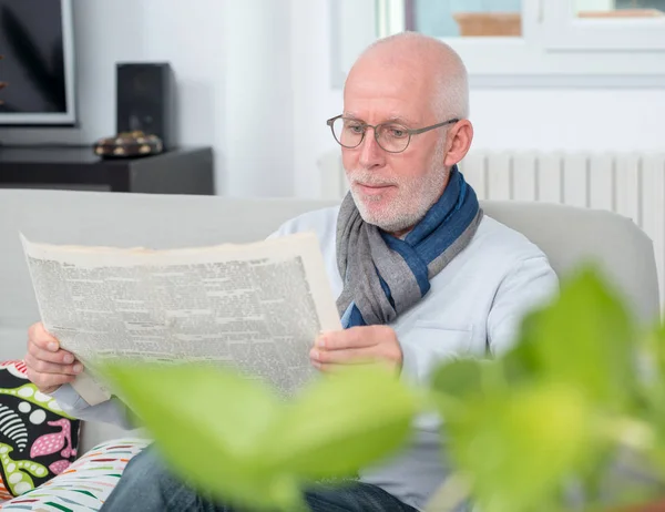 Przystojny mężczyzna dojrzałe z czytanie gazeta na kanapie — Zdjęcie stockowe