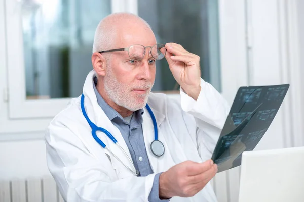 Volwassen arts kijken naar een röntgenfoto in een kantoor — Stockfoto