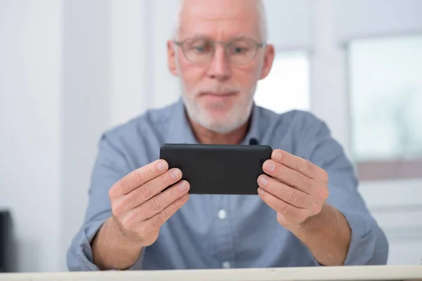 Mature handsome  man using smartphone at home — Stock Photo, Image