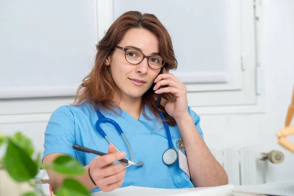 Dokter wanita muda berbicara di telepon — Stok Foto