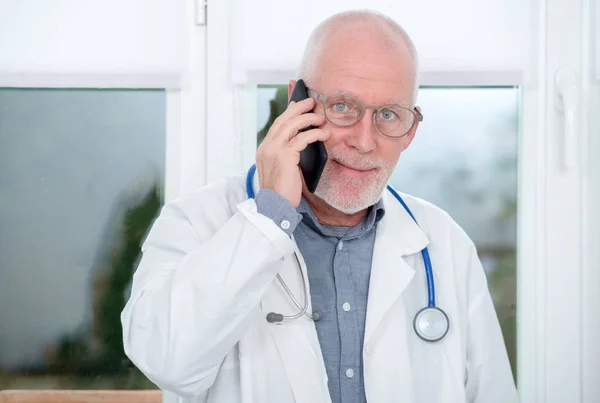 Volwassen arts op telefoon in zijn kantoor — Stockfoto