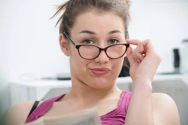 Молодая и улыбающаяся женщина в очках, читающая газету — стоковое фото