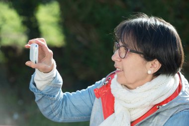 Smartphone, açık havada kullanan olgun esmer kadın