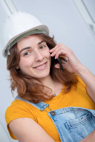 Jonge ingenieur vrouw met veiligheidshelm praten over telefoon — Stockfoto