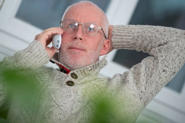 Przystojny mężczyzna senior rozmowy na telefon na kanapie — Zdjęcie stockowe