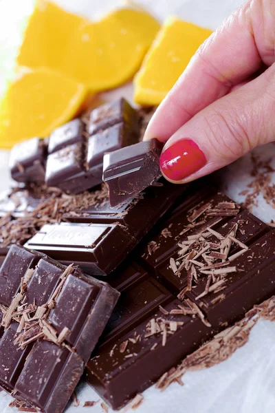 Tablet ve kadın parmak ile koyu çikolata parçaları — Stok fotoğraf