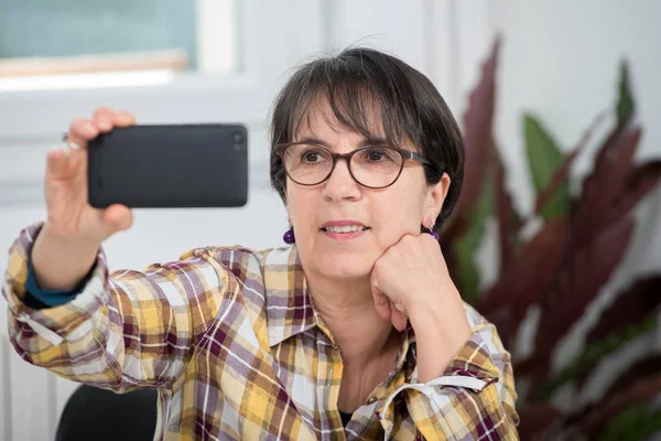 Mujer madura con camisa a cuadros haciendo selfie — Foto de Stock