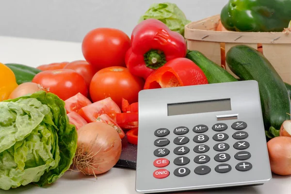 Legumes com uma calculadora na tabela branca — Fotografia de Stock