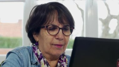 Evde kadın kıdemli dizüstü bilgisayar kullanan