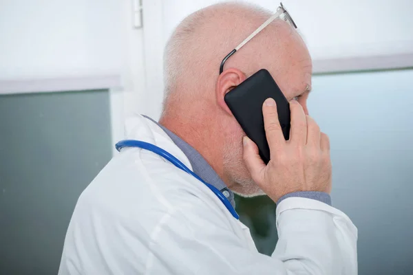 Mogen läkare på telefon i hans kontor — Stockfoto