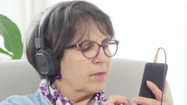 Orta yaş kadın evde smartphone ile müzik