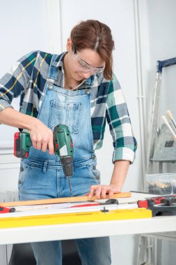 Elinde kablosuz matkap tutan güzel genç bir kadın.