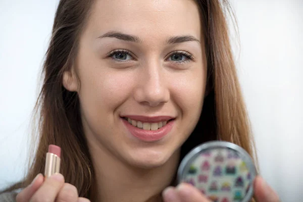 Giovane e sorridente donna mettendo rossetto — Foto Stock