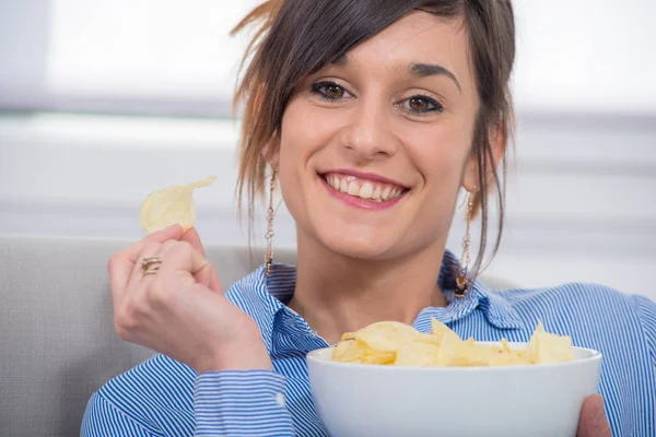 Jeune femme brune manger des chips — Photo