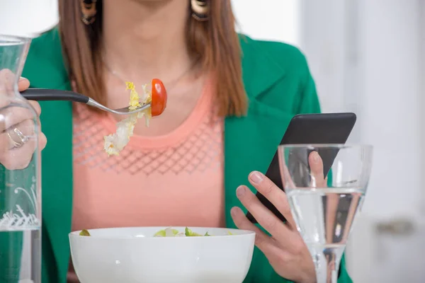 Joven morena mujer comiendo ensalada y teléfono —  Fotos de Stock