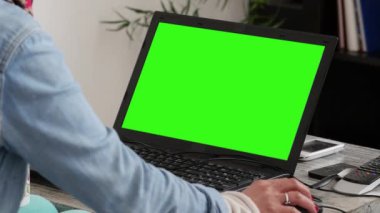 oturma odası, yeşil ekran bir dizüstü bilgisayar kullanan kadın