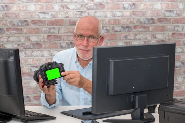 Fotógrafo con cámara en la oficina con ordenador, pantalla verde — Foto de Stock