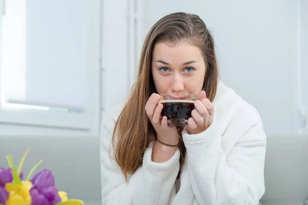Al mattino, una giovane e sorridente donna beve caffè — Foto Stock