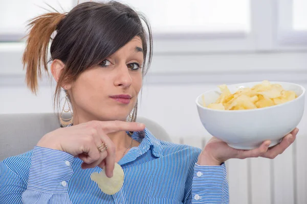 Ung brunett kvinna äter chips — Stockfoto