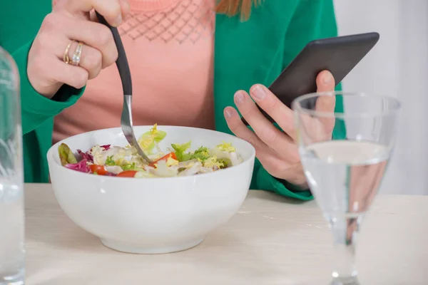 Jeune femme brune manger de la salade et téléphone — Photo