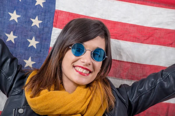 Young brunette with blue sunglasses in front of  american flag — Stock Photo, Image