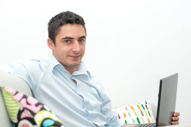 dizüstü bilgisayar ile kanepede oturan genç adam
