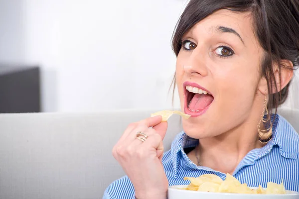 Jonge brunette vrouw chips eten — Stockfoto