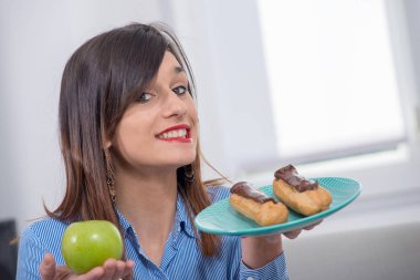 genç kadın bir elma ve çikolatalı pasta arasında seçim yapma