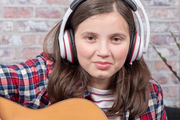 Uśmiechający się nastolatek ze słuchawkami, gra na gitarze — Zdjęcie stockowe