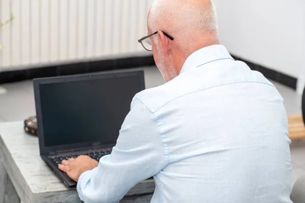 Senior man met laptop zitting in Bank — Stockfoto
