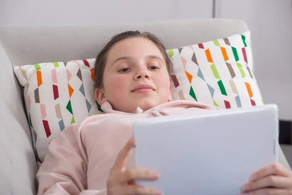 Joven adolescente chica usando tableta ordenador sentado en el sofá — Foto de Stock