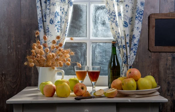 Bottle and glasses of cider with apples, near the window, in rus — Stock Photo, Image