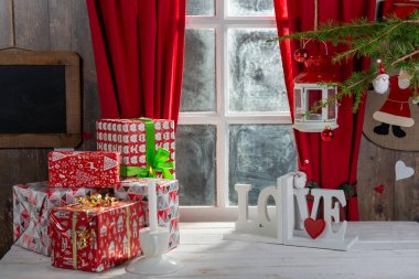 Noel hediyeleri masada, kırsal pencerenin yanında.