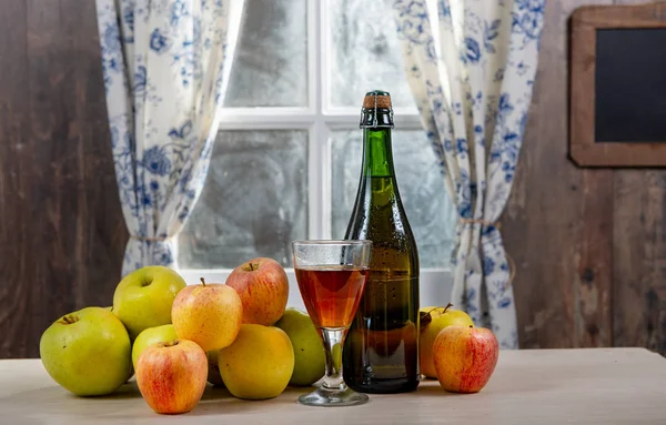 Fles en glas cider met appels. bij het raam, in rusti — Stockfoto