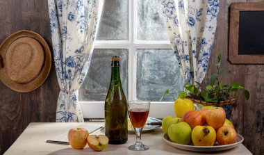 Elmalı bir şişe elma şarabı. Pencerenin yanında, Rusti 'de.