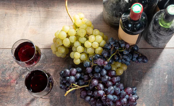 Deux verres à vin, raisins rouges et blancs avec bouteilles de vin rouge — Photo