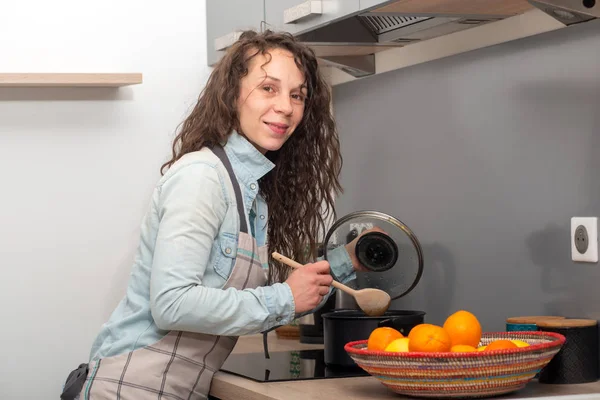 Mujer joven con el pelo largo está en la cocina — Foto de Stock
