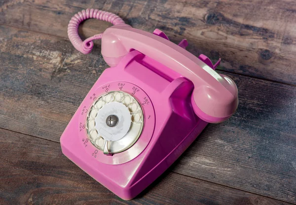 Retro růžový rotační telefon na dřevěném stole — Stock fotografie