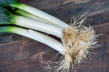Fresh raw leeks on wooden table