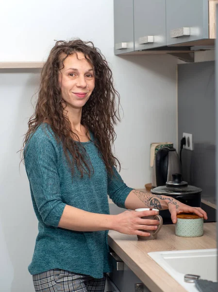 Mujer joven con el pelo largo está en la cocina — Foto de Stock