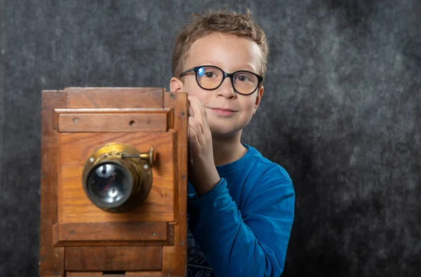 cheerful boy retro photographer with vintage wooden camera