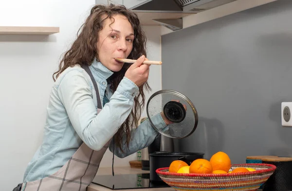 Mujer joven con el pelo largo está en la cocina — Foto de Stock